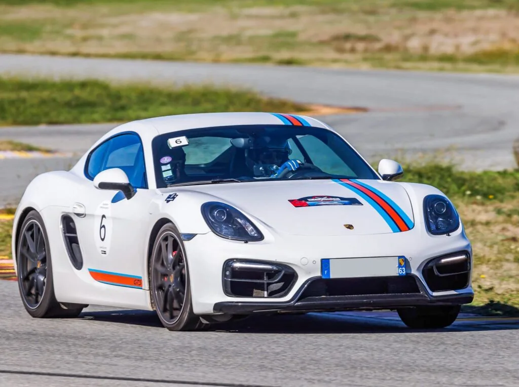 Porsche Cayman blanche avec bandes Martini sur circuit