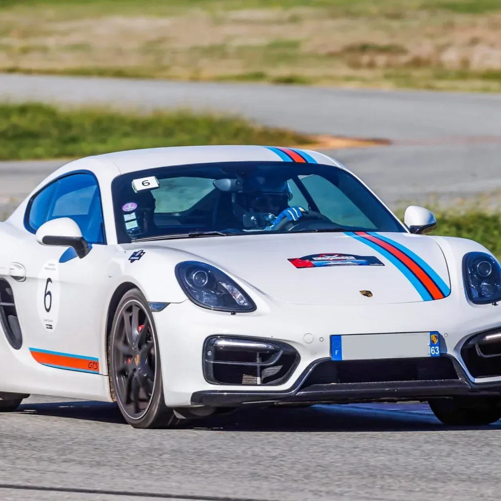 Porsche Cayman blanche avec bandes Martini sur circuit