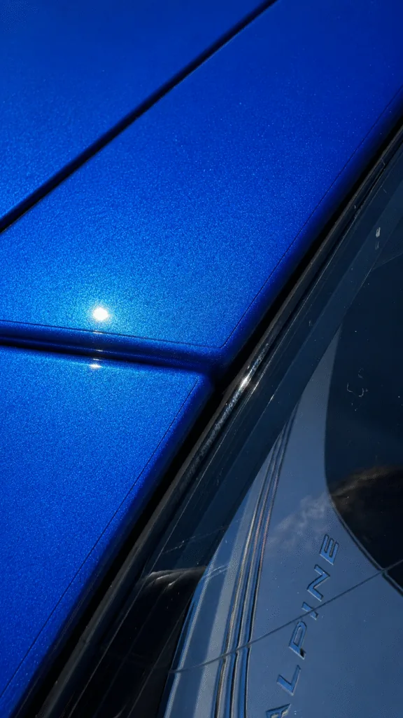 Gros plan sur une Alpine A110 Bleu Alpine montrant la discrétion du bord d’un film de protection PPF au niveau des jonctions de carrosserie.